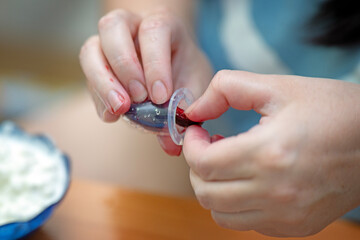 Woman's hands placing ripe cherry pieces into a silicone feeder