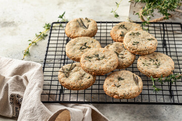 Shortbread cheese cookies with aromatic herbs on cooling rack on rustic textured background. Savory parmesan cookies for party