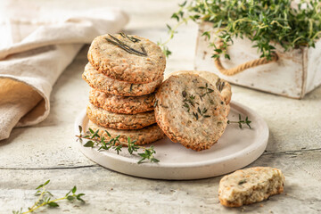 Shortbread cheese cookies with aromatic herbs on white plate on rustic textured background isolated. Savory parmesan cookies for party