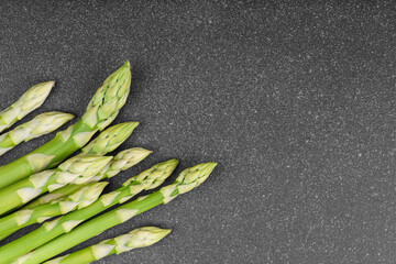 Bunch of raw fresh green asparagus stalks macro, close up on black textured background with copy...