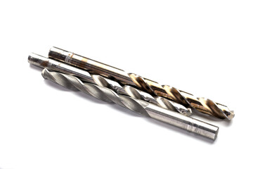 Two metal drill bits on a white background. One is straight and the other is twisted. They are used...