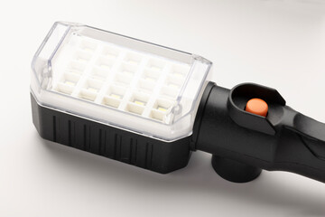 A portable LED lamp with a transparent cover and a black handle. The lamp is positioned on a white...
