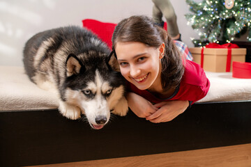 smiling girl and husky dog lie on bed. Christmas holiday celebration