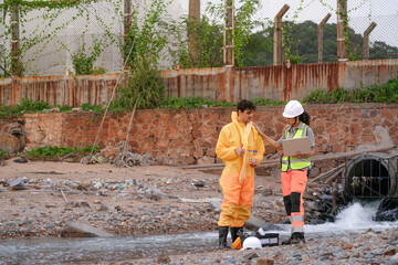 Environmental field team in protective gear analyzes water samples on a polluted beach. One holds a...