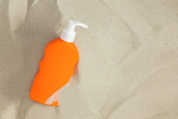 Close-up of orange tube of sunscreen on white sand. Sun protection. Top view