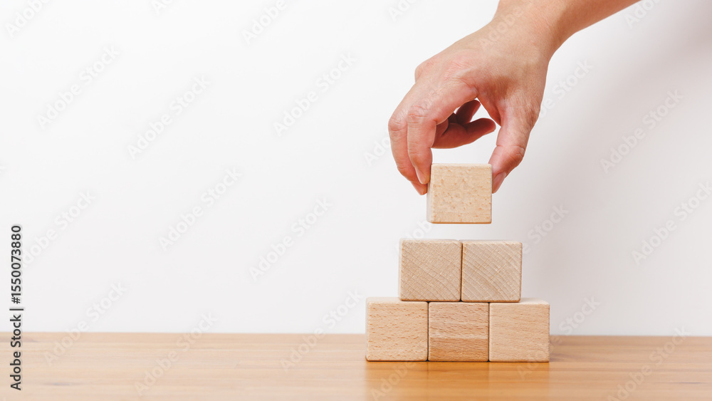 Poster man hand holding empty wooden blocks and stack up in white background. arranging of cube shape toy b