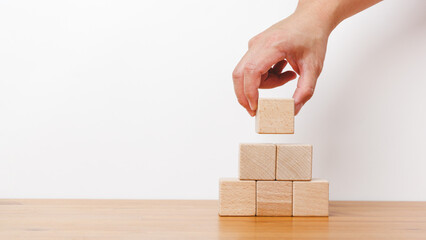 Man hand holding empty wooden blocks and stack up in white background. Arranging of cube shape toy blocks in business concept on building, progress or development.
