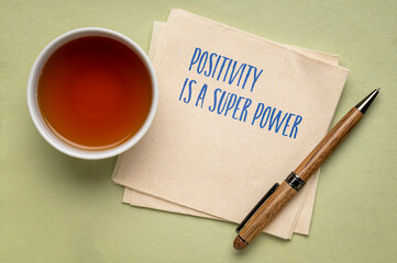 Positivity is a super power - inspiraitonal handwriting on a napkin with a cup of tea