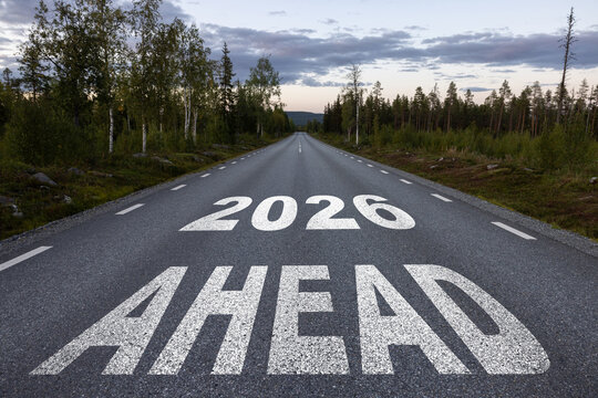 2026 New Year Background Design. Text 2026 written on the road in the middle of asphalt road at sunrise.
