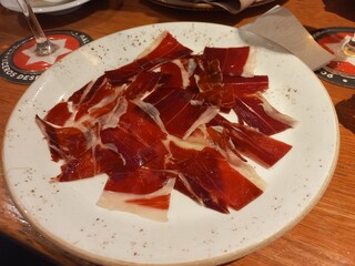 Sliced spanish jamon iberico on rustic plate in restaurant setting. Famous spanish tapas