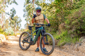 Happy senior cyclist gesturing shaka with electric mountain bike on trail