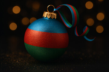 Christmas bauble in Azerbaijan flag colors with golden glitter and matching ribbon on dark background. Festive, patriotic holiday decoration concept