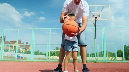 Father and daughter playing basketball together on a sports court, man leading the ball, excited child trying to take ball. Family having fun together - Powered by Adobe