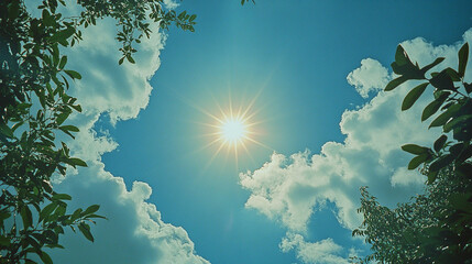 The sun shines through the clouds, creating a bright blue sky with white clouds. A lens flare is visible in front of it. Trees are visible in the distance.