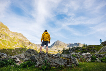 Solo hiker in yellow jacket exploring remote mountain terrain, enjoying panoramic view after...