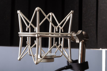 Silver spider microphone holder on a stand on a gray background