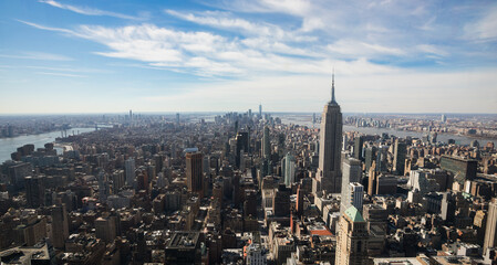 Panoramic aerial view of New York City on a sunny day with clouds in the background. Ideal for wallpapers and banners