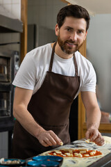 Man kneads dough in kitchen pressing firmly preparing pizza base