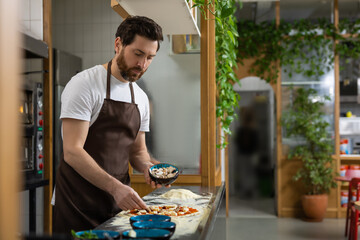 Man prepares pizza base in kitchen shaping dough carefully making meal