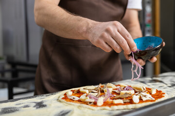 Man sprinkling onion on pizza