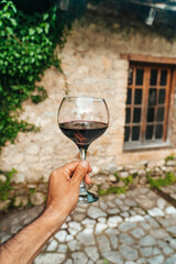 Red Wine Glass in Hand with Stone Cellar Background in France or Italy