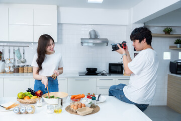 Happy portrait of loving young asian of having fun standing Take a photo after enjoy cook cooking with vegetables, meat, bread while standing on a kitchen Condo life or home
