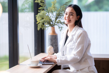 Asian freelance people business female talking making using casual working with laptop computer and coffee at home in the living room indoors artificial rose bouquet of red and pink roses rose vase
