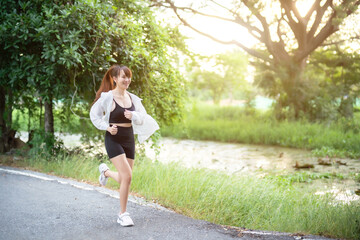 Portrait of beautiful asian Young woman in white robe wearing sportswear jogging working out outside. training on public equipment in outdoor at park. concept Exercise Healthy lifestyle.