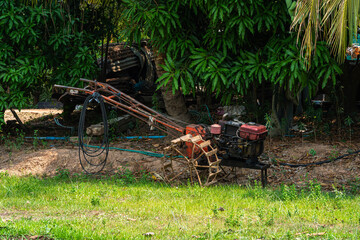 walking tractor rotativo used to pump water to Banana tree plantation,Coconut Garden integrated agriculture nature the garden with daylight blue sky white clouds in Thailand.