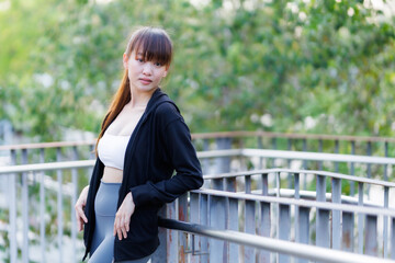 Portrait of beautiful asian Young woman in Black robe sportswear working out outside. training on public equipment in outdoor at park. concept Exercise Healthy lifestyle.