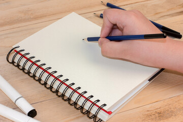 Hand draws on a notebook with a pencil