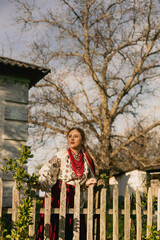 Ukrainian woman in traditional clothing leaning on a wooden fence