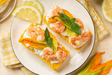 Top view of bruschetta or open sandwich with pumpkin bread, shrimps, prawns and burrata cheese with Zucchini Flowers or Italian Squash Blossom.