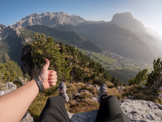 Close up legs in hiking shoes sitting person on edge of Alps mountains