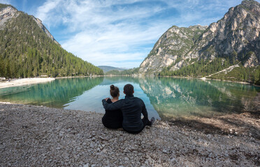 Couple in love sitting on the shore of a lake in the mountains