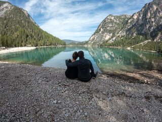 Couple in love sitting on the shore of a lake in the mountains
