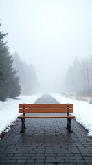 A solitary bench sits on a cobblestone path, blanketed in snow, amidst a foggy forest.