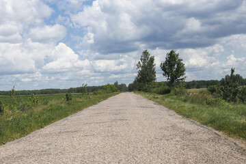 Straight country road view. Rural paved street through green landscape. Empty road disappearing in...