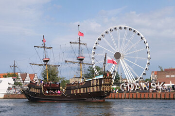 Observation wheel, galleon cruise ship and the capital letters GDANSK on the Motława River coast...