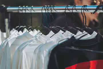 Rows of crisp white tees hanging out alongside a bold, black and red one, all suspended on black...