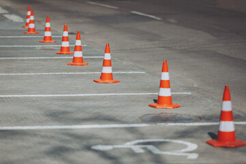 Orange sentinels stand guard over empty parking spaces, their presence a silent reminder of rules,...