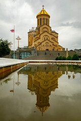 Reflection of a grand church in serene water under an overcast sky in a historic city