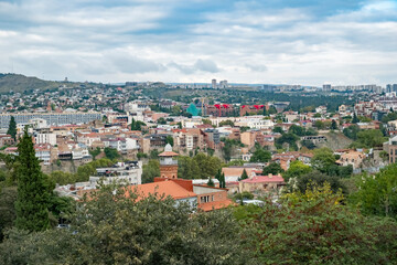 Fototapeta premium Stunning view of Tbilisi showcasing historic architecture and modern cityscape under a cloudy sky