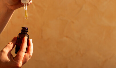 Womans hand using pipette to dispense luxury facial oil on neutral background. Perfect for skincare routines organic beauty cosmetic product ads.