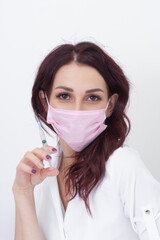 A young doctor in a mask holds a syringe for vaccination.