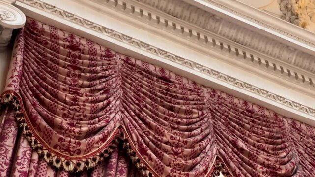 Traditional English interior cornice with deep red damask swags and detailed plasterwork, evoking a refined heritage drawing room, slow motion