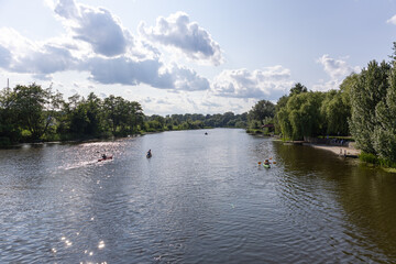 Group of kayakers paddling on river in summer day from rear view