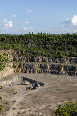 Open-Pit Quarry with Rock Layers and Green Forest Background