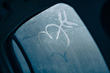 Heart pierced by an arrow. Drawing on a fogged car window