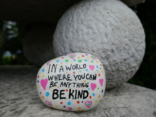 Old stone statue ball with be kind kindness rock
